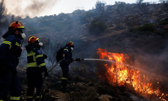 Firefighters and volunteers try to extinguish a wildfire near Vari in south of Athens, Greece, on June 4, 2022. (Costas Baltas/Reuters)