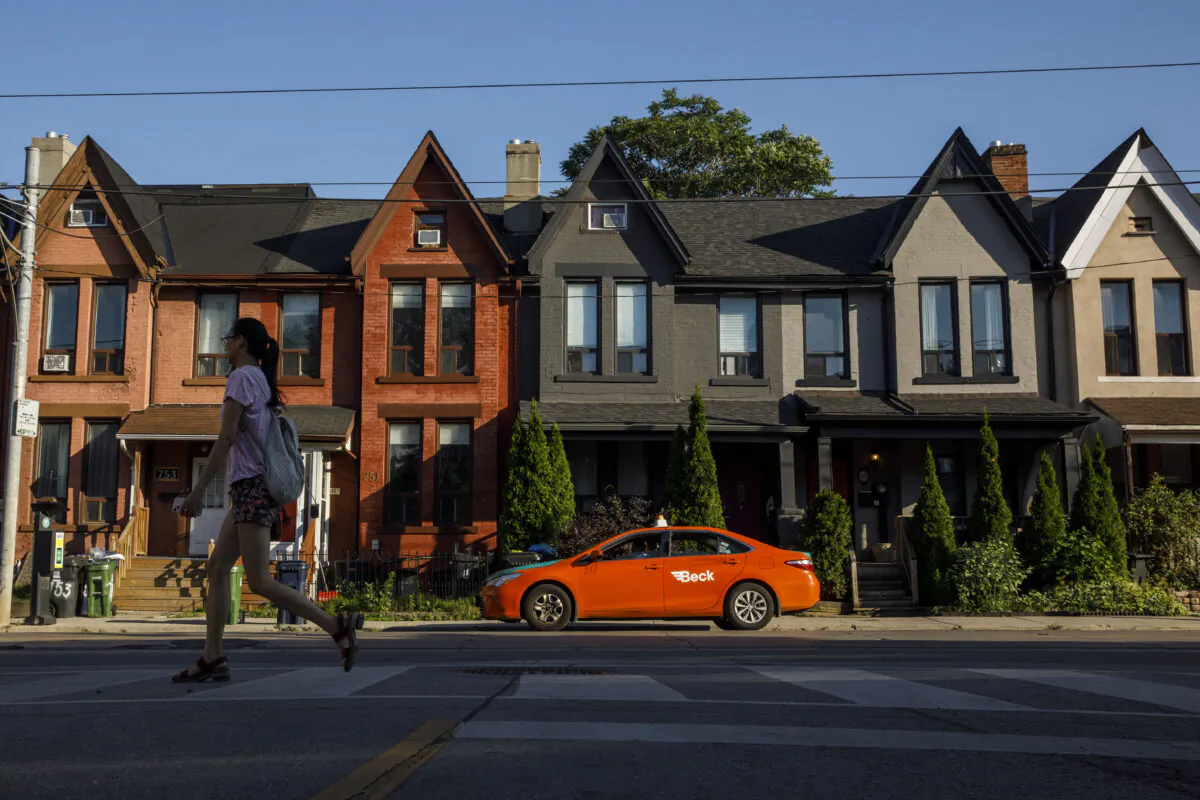 A person walks by a row of houses in Toronto on July 12, 2022. (The Canadian Press/Cole Burston)