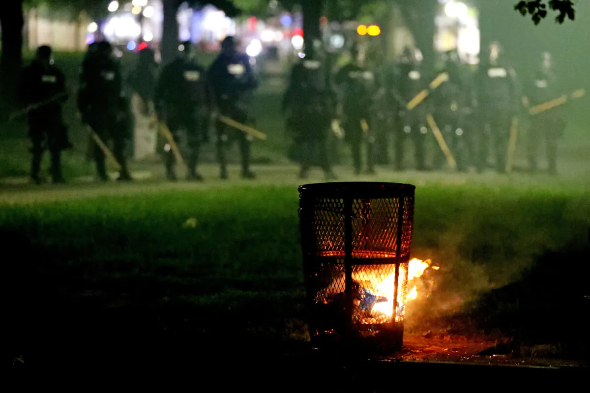 Police officers stand behind a lit trash can on Boston Common during a protest in response to the death of George Floyd on May 31, 2020. Protests spread across the United States in response to the death of George Floyd while in police custody in Minneapolis, Minnesota. (Maddie Meyer/Getty Images)