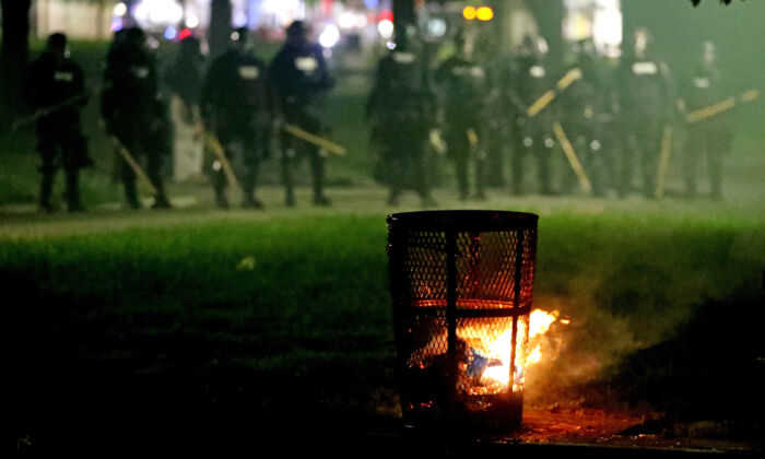 Police officers stand behind a lit trash can on Boston Common during a protest in response to the death of George Floyd on May 31, 2020. Protests spread across the United States in response to the death of George Floyd while in police custody in Minneapolis, Minnesota.  (Maddie Meyer/Getty Images)