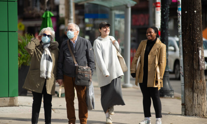 An elderly couple wearing masks wait to cross Ossington St. next to two unmasked younger women, Toronto, on Oct. 28, 2021. (The Canadian Press/Eduardo Lima)