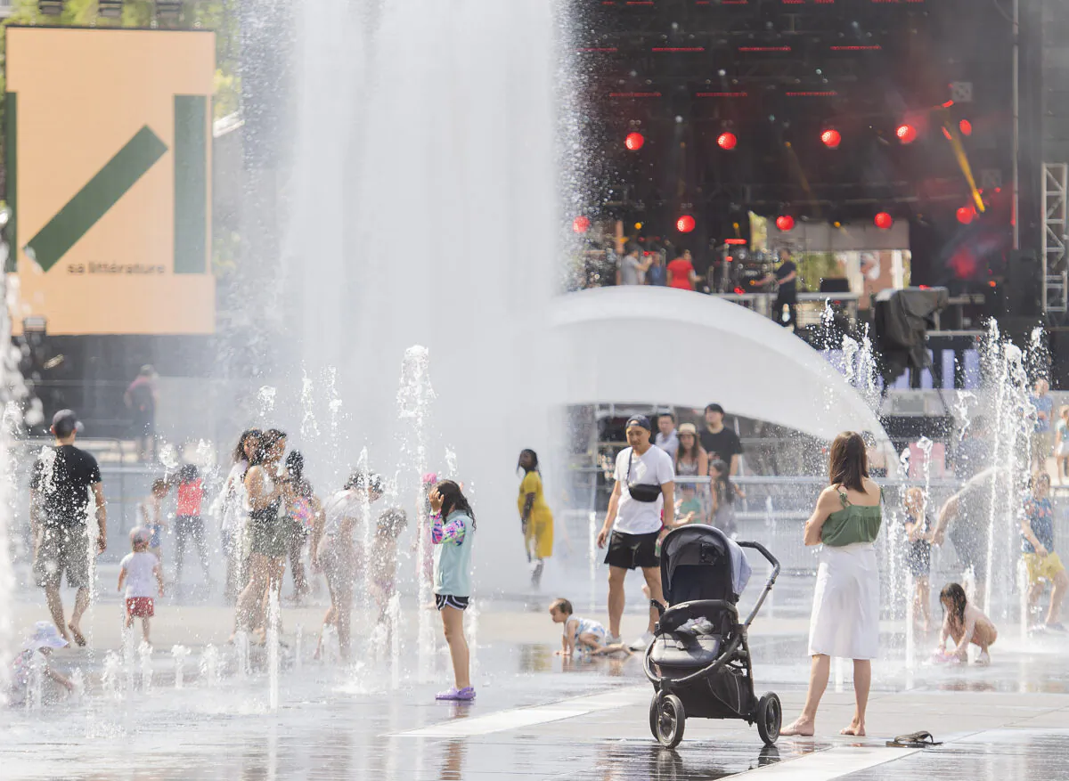 People cool off in water fountains in Montreal, Saturday, July 2, 2022. (The Canadian Press/Graham Hughes)