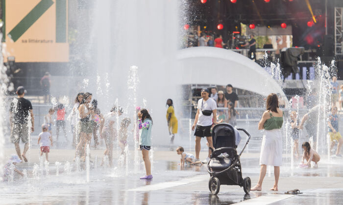 People cool off in water fountains in Montreal, Saturday, July 2, 2022. (The Canadian Press/Graham Hughes)
