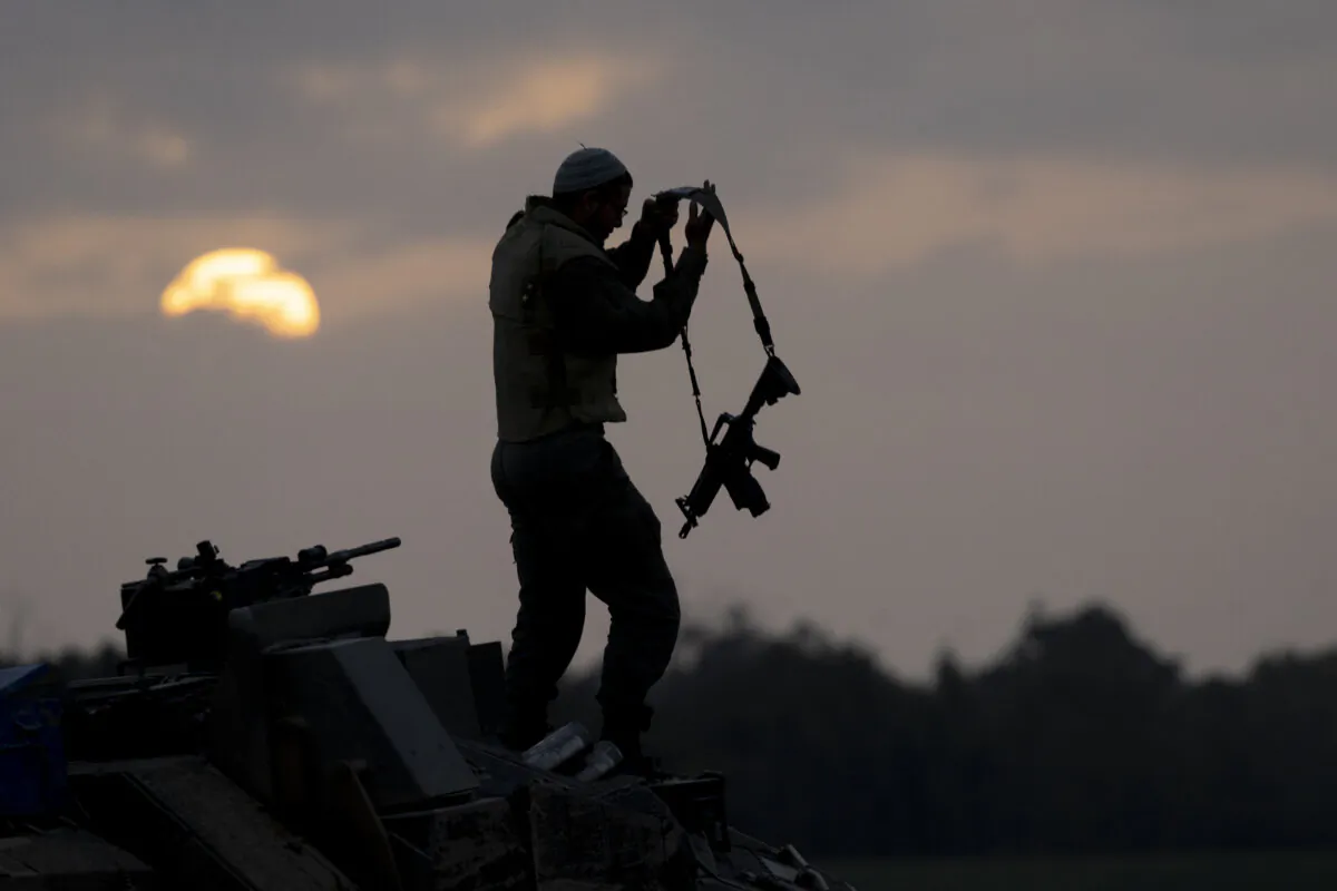 An Israeli soldier stands on a tank as it takes position in front of the northern Gaza Strip as seen from a position on the Israeli side of the border on March 18, 2025, as Gaza fighting resumed. (Amir Levy/Getty Images)