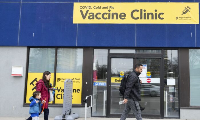 People walk past a COVID-19 vaccine clinic in Mississauga, Ont., on April 13, 2022. (The Canadian Press/Nathan Denette)