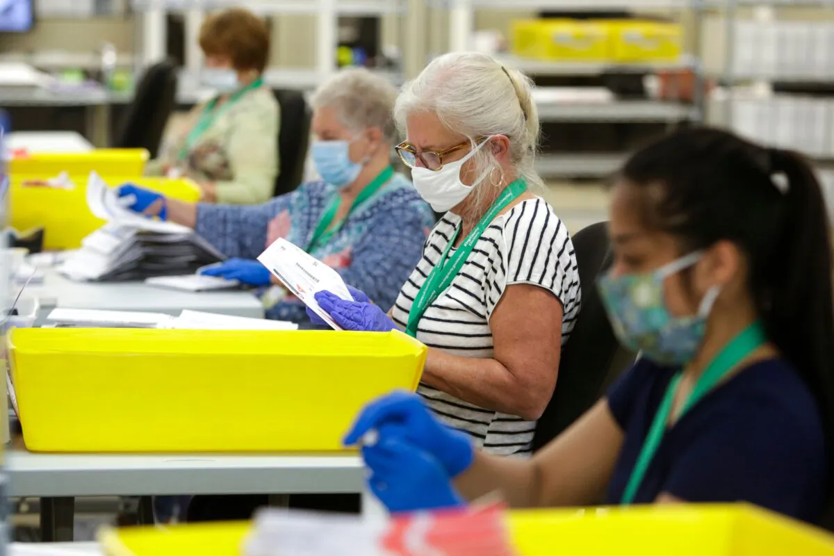 Election workers wear masks and gloves as they open envelopes containing vote-by-mail ballots for the August 4 Washington state primary at King County Elections in Renton on August 3, 2020. (Jason Redmond/AFP via Getty Images)