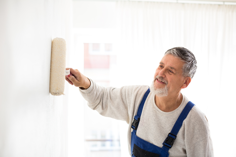 Senior,Man,Painting,A,Wall,In,His,Home,,Smiling,,Enjoying