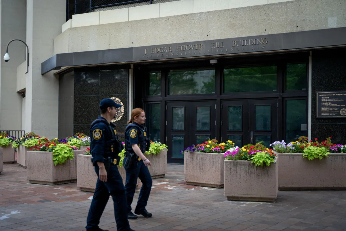 Law enforcement officers walk past the J. Edgar Hoover FBI Building in Washington on July 21, 2022. (Chung I Ho/The Epoch Times)