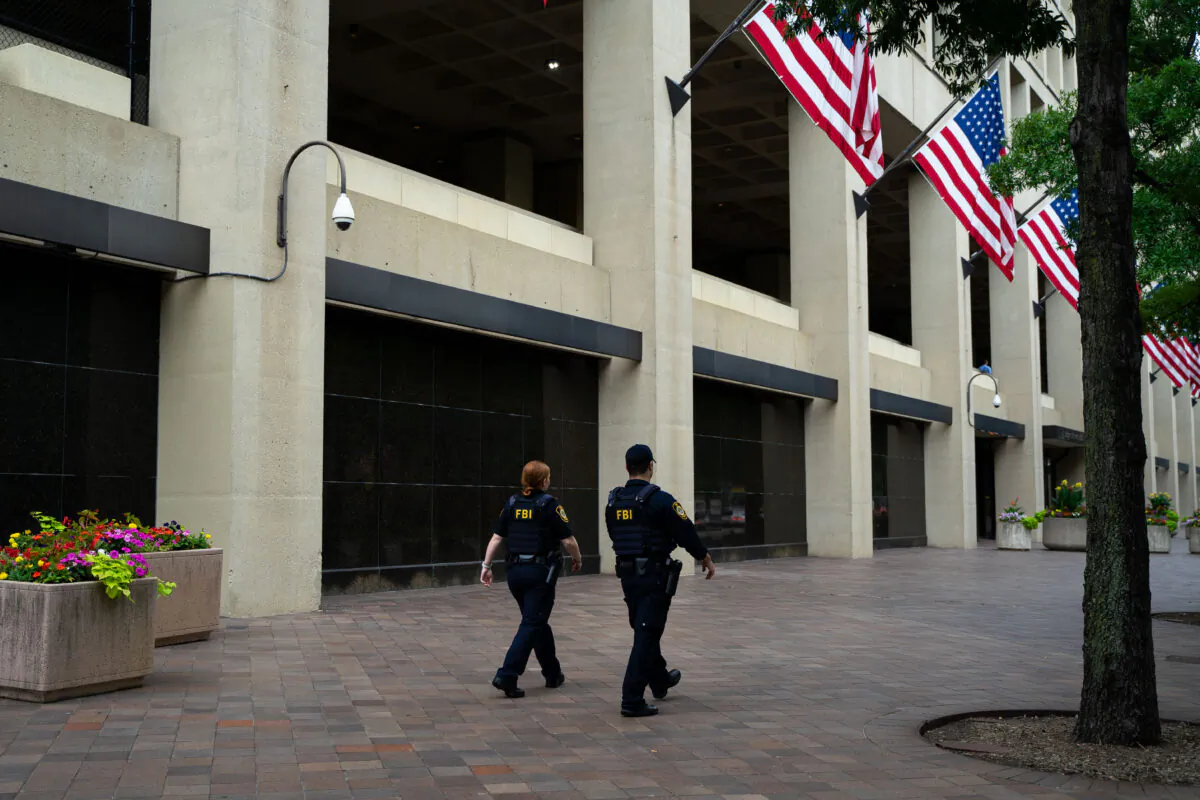 Law enforcement officers walk past the J. Edgar Hoover FBI Building in Washington on July 21, 2022. (Chung I Ho/The Epoch Times)