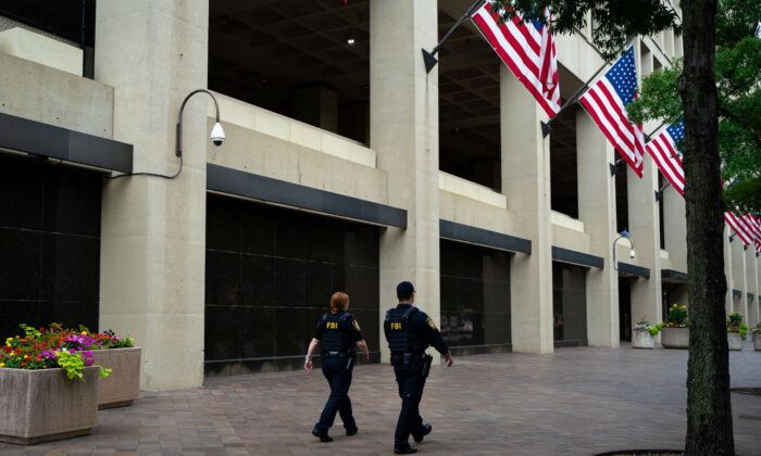 Law enforcement officers walk past the J. Edgar Hoover FBI Building in Washington on July 21, 2022. (Chung I Ho/The Epoch Times)