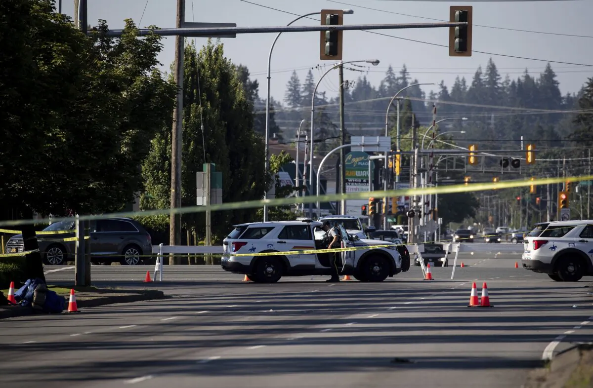 An RCMP officer stands outside a vehicle at a roadblock at the scene of a shooting in Langley, B.C., on July 25, 2022. (Darryl Dyck/The Canadian Press via AP)