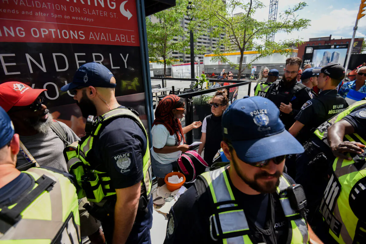 Officers from the Ottawa Police Service (OPS) surround protestors who set up a table during a rally in support of Dutch farmers and Freedom Fighters Canada near the Embassy of the Kingdom of the Netherlands to Canada in Ottawa on July 23, 2022. (The Canadian Press/Spencer Colby)