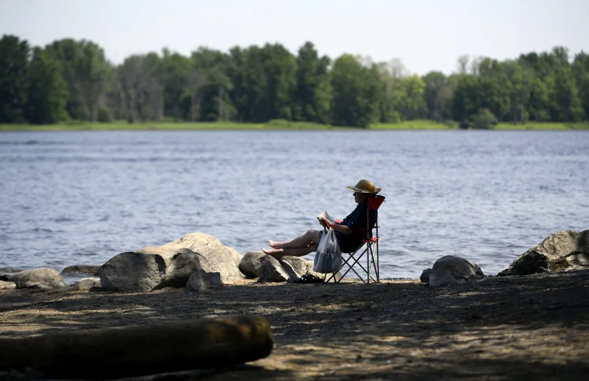 A woman reads a book by the Ottawa River in Ottawa on June 6, 2021. (The Canadian Press/Justin Tang)