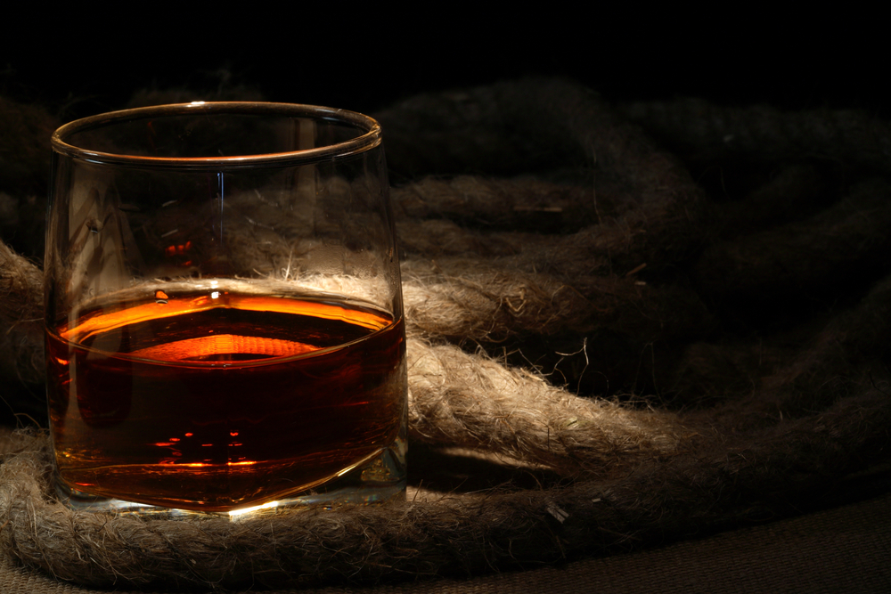 Closeup,Of,Glass,Of,Rum,Near,Rope,On,Dark,Background