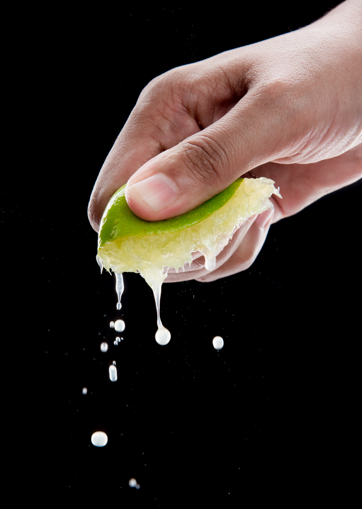 Hand,Squeeze,Lime,With,Lime,Drop,On,Black,Background