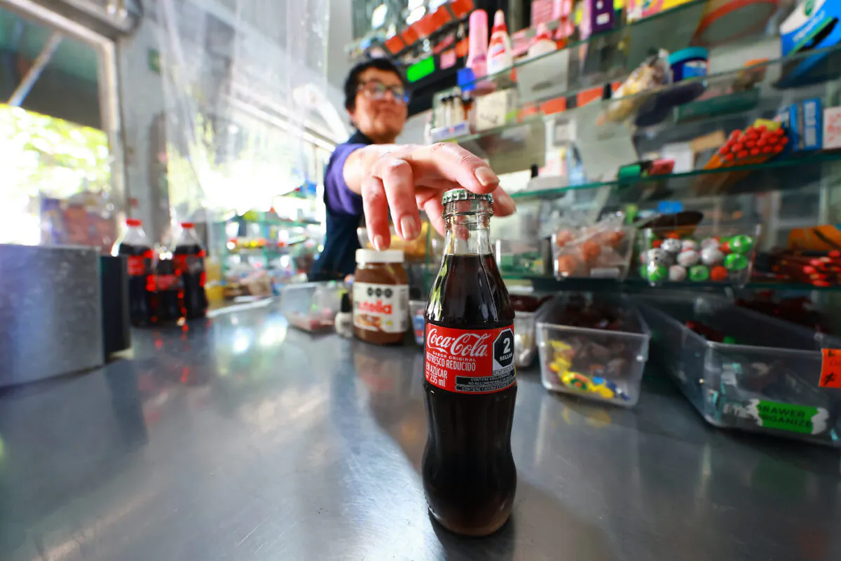A saleswoman grabs a Coca-Cola to pass it through the price reader in Mexico City on June 3, 2022. (Hector Vivas/Getty Images)
