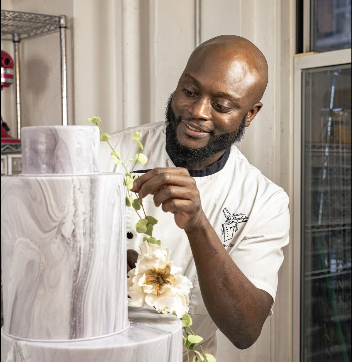 Pastry chef Ebow Dadzie decorates a cake with handmade sugar flowers at his Manhattan studio. (Tatsiana Moon for American Essence)