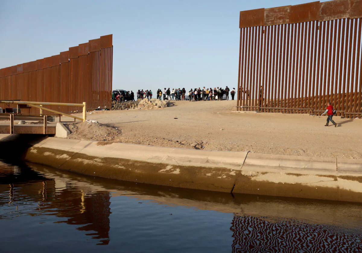 Illegal immigrants near a gap in the U.S.-Mexico border barrier, awaiting processing by the U.S. Border Patrol in Yuma, Arizona, on May 20, 2022. (Mario Tama/Getty Images)