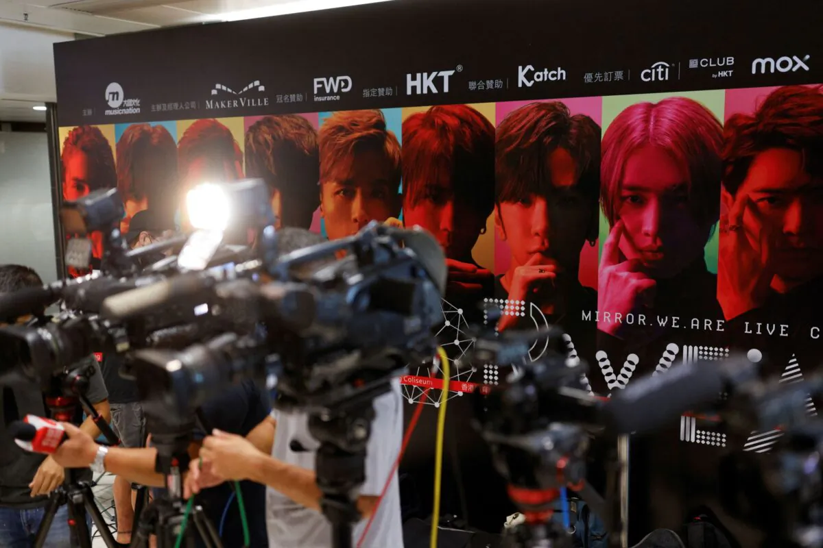 Members of the media stand in front of a background showing Hong Kong boyband Mirror during a news conference after a giant video panel fell onto the stage during a concert, in Hong Kong, on July 29, 2022. (Tyrone Siu/Reuters)