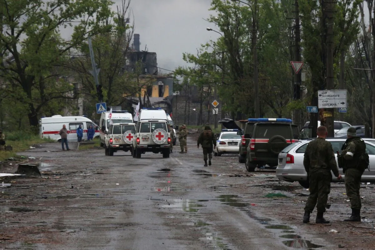 Red Cross staff drive by in their vehicles to the besieged Mariupol's Azovstal steel plant to observe the evacuation of Ukrainian servicemen from Azovstal steel plant, in Mariupol, eastern Ukraine, on May 18, 2022. (AP Photo)