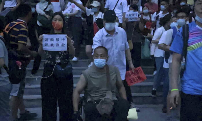 10 juillet 2022, des personnes tenant des banderoles organisent une manifestation devant la succursale de la banque centrale de Chine à Zhengzhou, dans la province du Henan (centre de la Chine). Une grande foule de déposants bancaires chinois en colère ont affronté la police le 10 juillet, certains auraient été blessés alors qu'ils étaient brutalement emmenés, dans une affaire qui a attiré l'attention en raison de tentatives antérieures d'utilisation d'une application de suivi COVID-19 pour les empêcher de se mobiliser . (Photo AP/Yang)