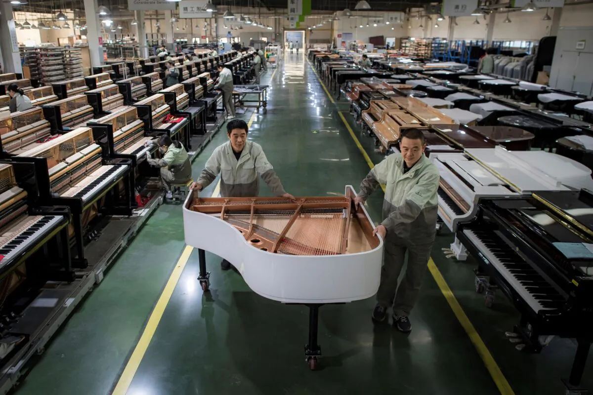 Workers transfer a half-assembled piano at a production factory of Parsons Music Corporation in Yichang, central China's Hubei Province, on Nov. 23, 2021. (Xiao Yijiu/Xinhua via AP)