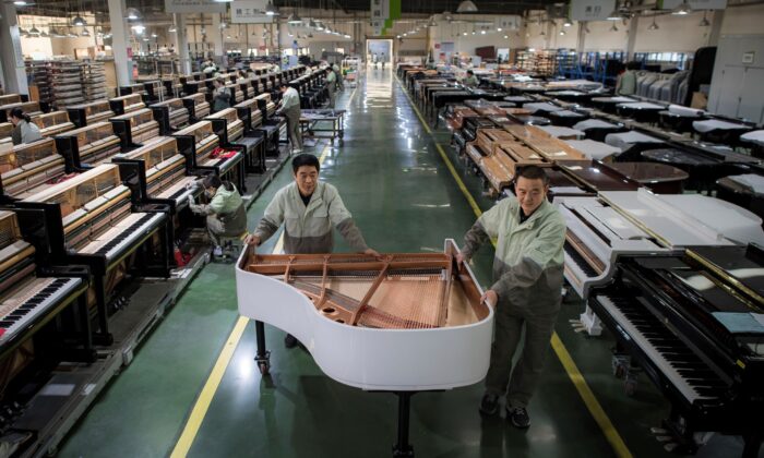 Workers transfer a half-assembled piano at a production factory of Parsons Music Corporation in Yichang, central China's Hubei Province, on Nov. 23, 2021. (Xiao Yijiu/Xinhua via AP)