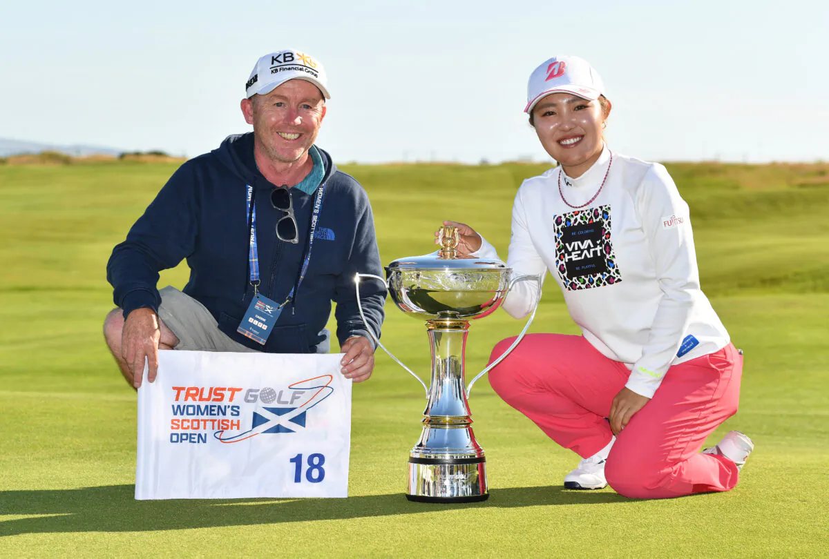 Ayaka Furue of Japan poses with her caddie Michael Scott at the 18th green with the trophy, as she wins the Trust Golf Women's Scottish Open during the final round of the Trust Golf Women's Scottish Open at Dundonald Links Golf Course in Troon, Scotland, on July 31, 2022. (Mark Runnacles/Getty Images)