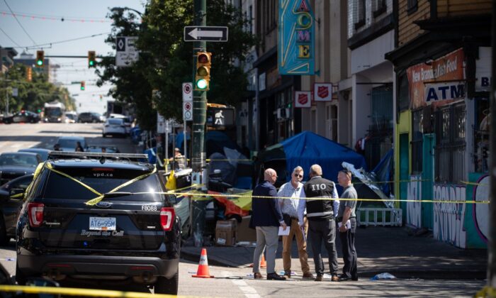 2022 年 7 月 30 日，独立调查办公室 (IIO) 的一名成员在温哥华市中心东区发生枪击事件的警察现场与其他调查人员交谈。（加拿大新闻社/Darryl Dyck）