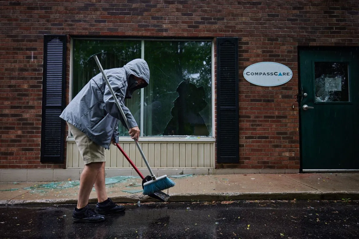 An employee cleans up broken glass in the aftermath of a firebombing at CompassCare pregnancy center in Amherst, N.Y., on June 7, 2022. (Dan Berger/The Epoch Times)