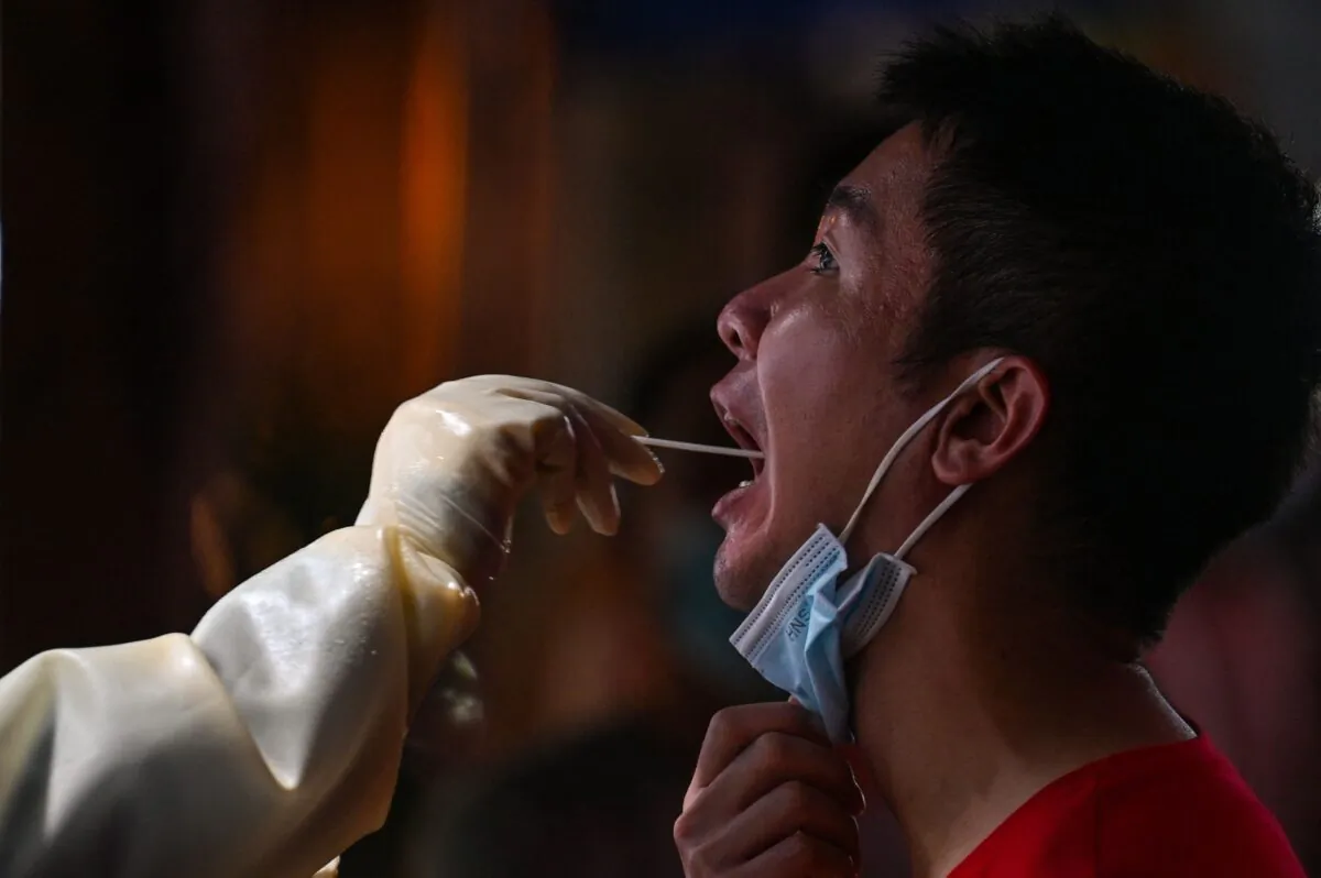 A health worker takes a swab sample from a man to test for COVID-19 in the Jing'an district of Shanghai, China on July 31, 2022. (Hector Retamal/AFP via Getty Images)