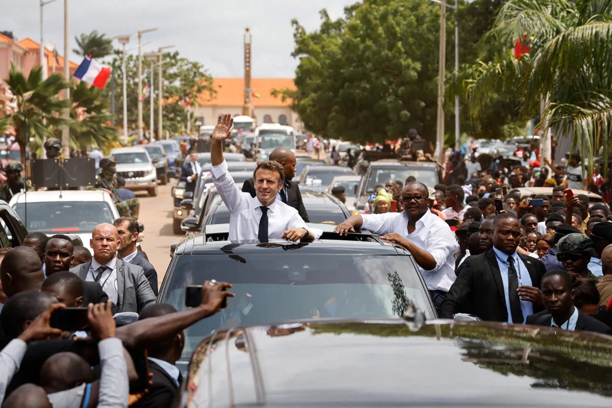 French president Emmanuel Macron and Guinea-Bissau's president Umaro Sissoco Embalo (R) wave to the crowd through the roof of a car in Bissau, on July 28, 2022. (Ludovic Marin/AFP via Getty Images)