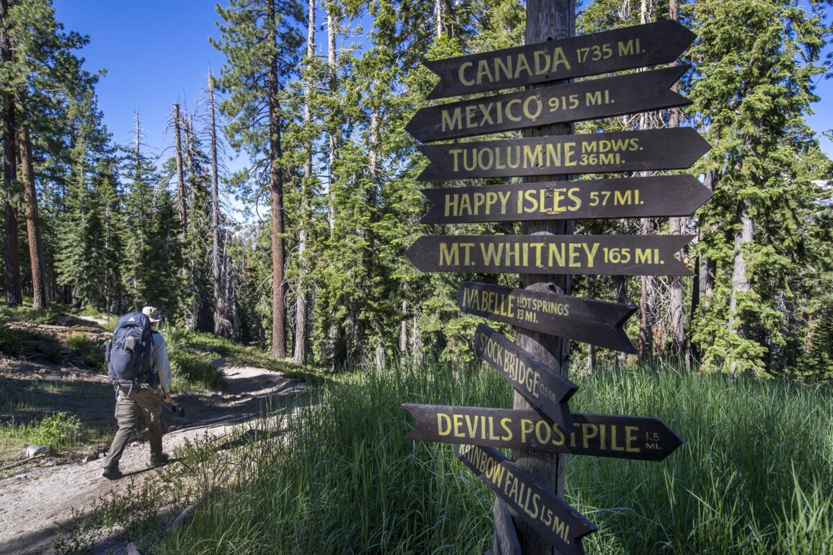 A hiker on the Pacific Crest Trail passes signs near Red's Meadow Resort & Pack Station, located at an elevation of 7,500 feet on June 21, 2022, in Mammoth Lakes, California. (Allen J. Schaben/Los Angeles Times/TNS)