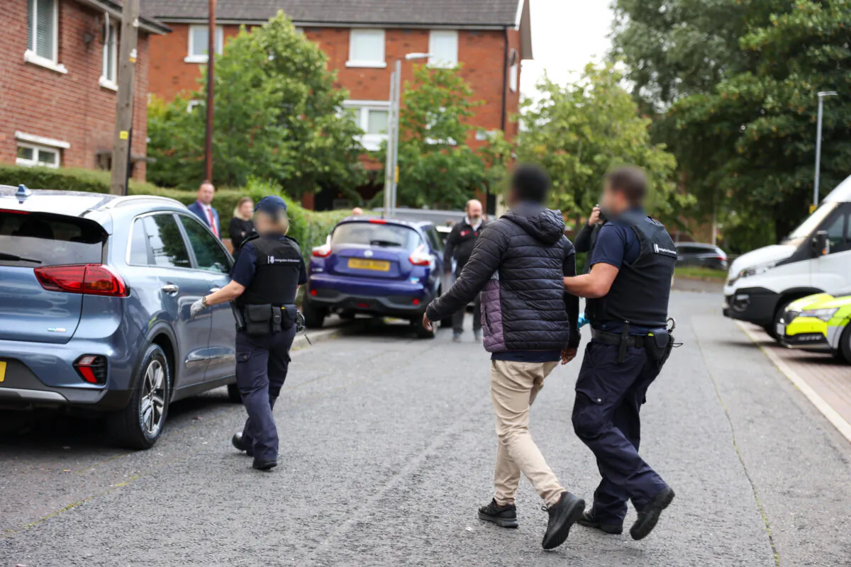 Police officers arrest a 40-year-old woman and a 26-year-old man in Belfast, Northern Ireland, UK, on Aug. 3, 2022. (PA Media/Home Office)