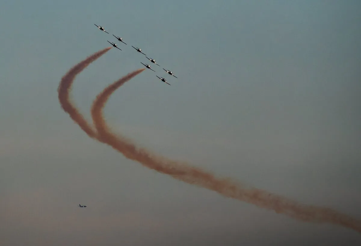 The Canadian Forces Snowbirds air demonstration team fly over English Bay as part of the Celebration of Light fireworks festival, in Vancouver, as an aircraft on approach to land at Vancouver International Airport is seen in the distance, on July 27, 2022. (The Canadian Press/Darryl Dyck)