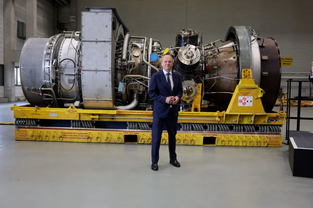 German Chancellor OIaf Scholz stands next to a gas turbine meant to be transported to the compressor station of the Nord Stream 1 gas pipeline in Russia during his visit to Siemens Energy's site in Muelheim an der Ruhr, Germany, on Aug. 3, 2022. (Wolfgang Rattay/Reuters)