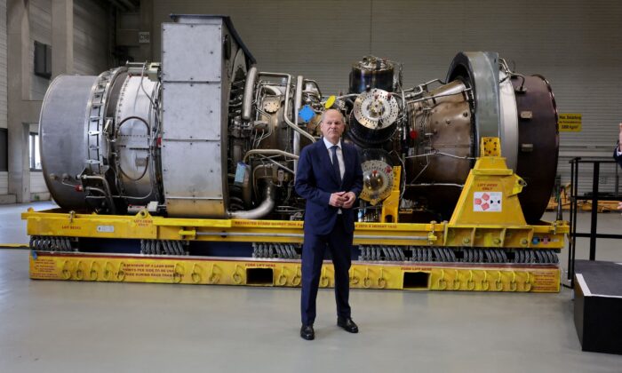 German Chancellor OIaf Scholz stands next to a gas turbine meant to be transported to the compressor station of the Nord Stream 1 gas pipeline in Russia during his visit to Siemens Energy's site in Muelheim an der Ruhr, Germany, on Aug. 3, 2022. (Wolfgang Rattay/Reuters)