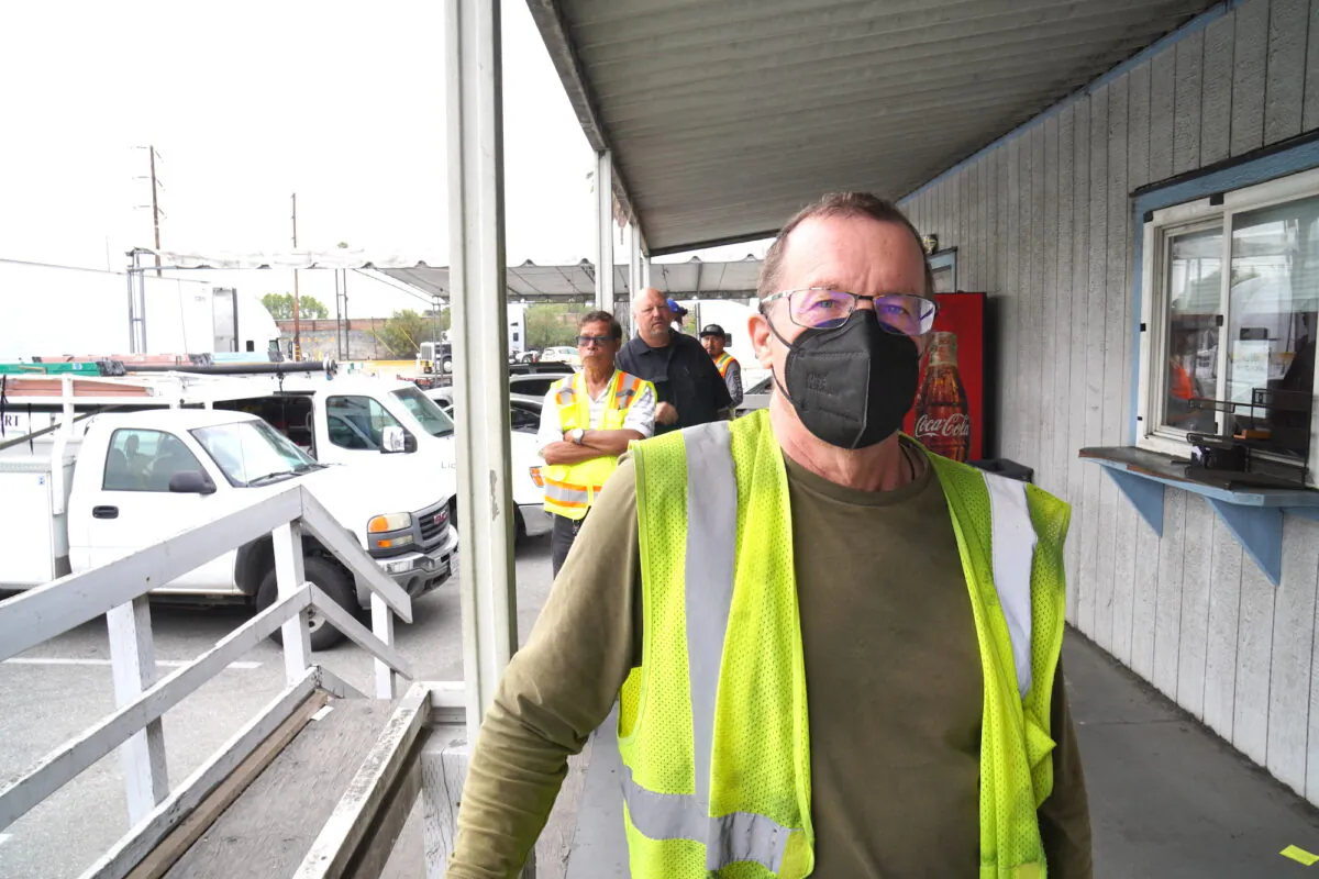 Michael Clifford, a company truck driver from Utah, waits in life for his entry papers at a transportation logistics company in Long Beach, Calif., on July 26, 2022. Clifford said he thinks California's new state labor law redefining owner-operators as employees will hurt the industry long term. (Allan Stein/The Epoch Times)