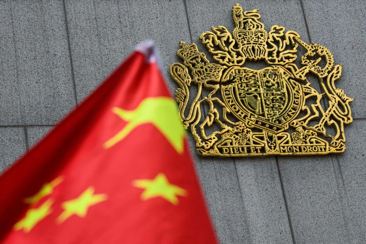 The royal coat of arms of the United Kingdom (R) is seen next to the national flag of China as pro-Beijing activists gather outside the British Consulate-General to protest against the use of the British National (Overseas) passport, in Hong Kong on Feb. 1, 2021. (Anthony Wallace/AFP via Getty Images)