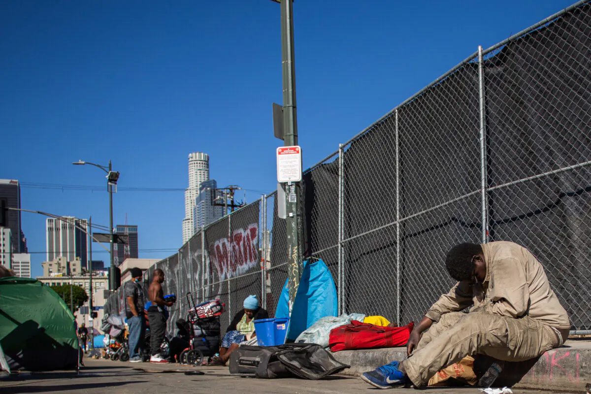 Homeless people sit on the sidewalk by the nonprofit Midnight Mission's headquarters, in the Skid Row neighborhood of downtown Los Angeles on Nov. 25, 2021. (APU GOMES/AFP via Getty Images)