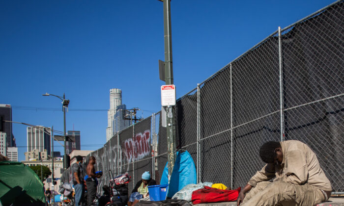 Homeless people sit on the sidewalk by the nonprofit Midnight Mission's headquarters, in the Skid Row neighborhood of downtown Los Angeles on Nov. 25, 2021. (APU GOMES/AFP via Getty Images)