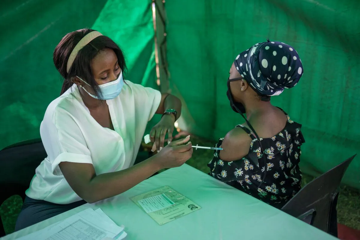 A healthcare worker administers the Johnson & Johnson COVID-19 vaccine to a woman outside a polling station at the Kopanong Hall in Soweto, South Africa, on Nov. 1, 2021. (Michele Spatari/AFP via Getty Images)