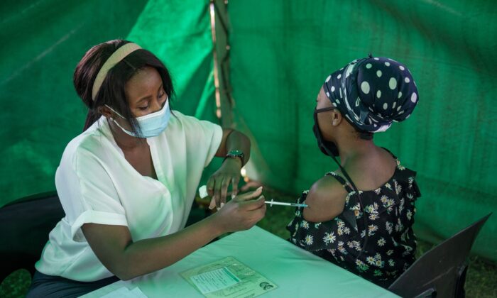 A healthcare worker administers the Johnson & Johnson COVID-19 vaccine to a woman outside a polling station at the Kopanong Hall in Soweto, South Africa, on Nov. 1, 2021. (Michele Spatari/AFP via Getty Images)