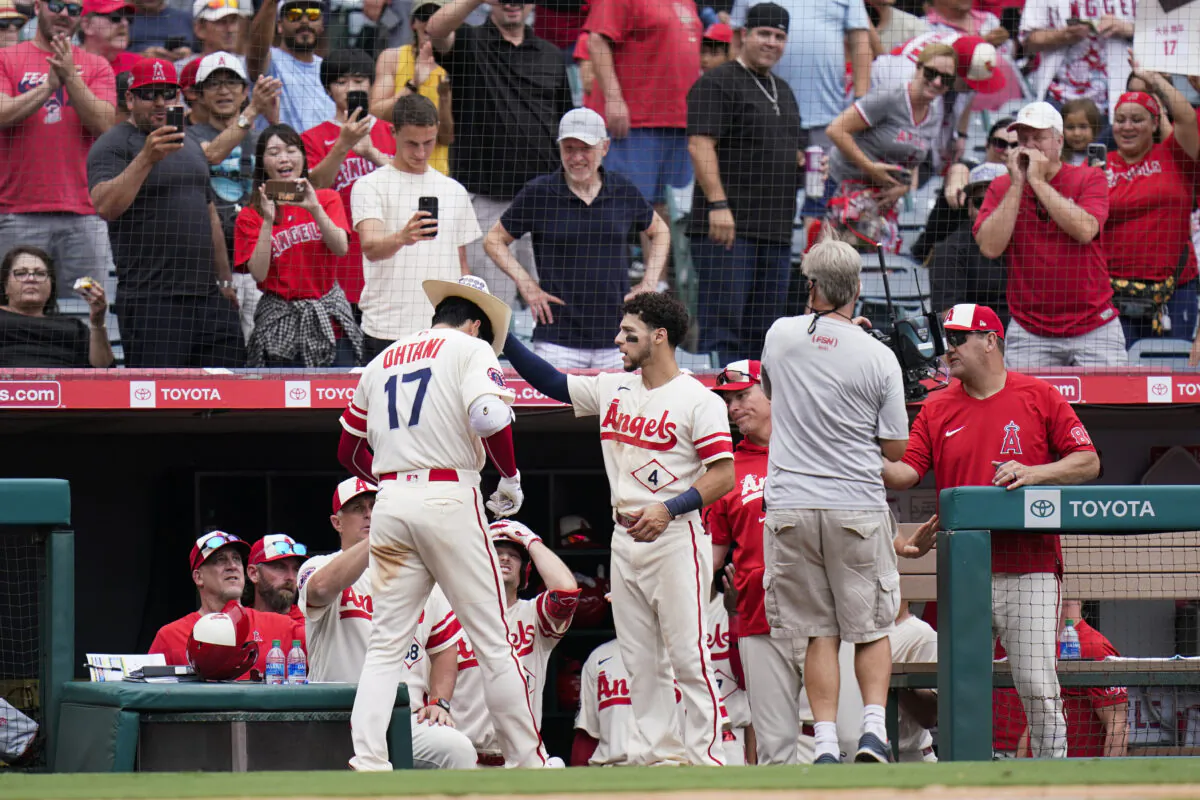 Fans cheer as Los Angeles Angels' Andrew Velazquez (4) puts a cowboy hat onto Shohei Ohtani (17) after Ohtani's second home run of the baseball game, during the seventh inning against the Oakland Athletics in Anaheim, on Thursday, Aug. 4, 2022. (Jae C. Hong/AP Photo)