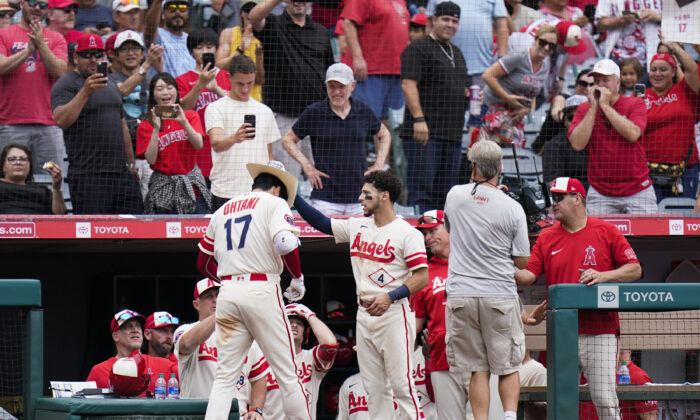 Fans cheer as Los Angeles Angels' Andrew Velazquez (4) puts a cowboy hat onto Shohei Ohtani (17) after Ohtani's second home run of the baseball game, during the seventh inning against the Oakland Athletics in Anaheim, on Thursday, Aug. 4, 2022. (Jae C. Hong/AP Photo)