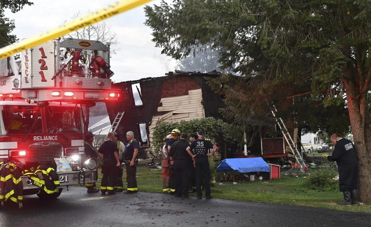 Firefighters gather next to a home after an early morning fatal fire at 733 First Street in Nescopeck, Pa., on Aug. 5, 2022. (Jimmy May/Bloomsburg Press Enterprise via AP)