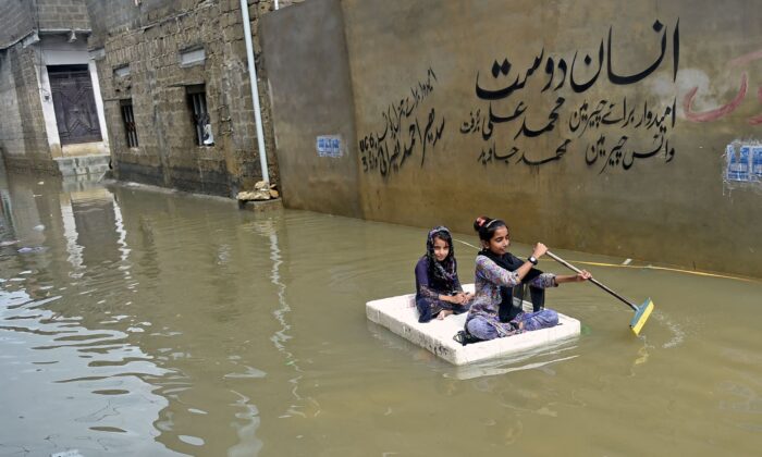 Girls use a temporary raft across a flooded street in a residential area after heavy monsoon rains in Karachi on July 26, 2022. (Rizwan Tabassum/AFP via Getty Images)