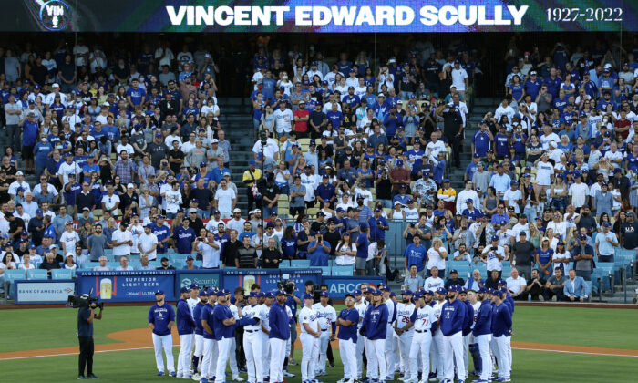Los Angeles Dodgers players and coaches stand on the field as late Hall of Fame broadcaster Vin Scully is honored during a pregame ceremony prior to the game between the San Diego Padres and the Los Angeles Dodgers at Dodger Stadium. Scully passed away at age 94 on August 2, 2022; in Los Angeles, August 5, 2022. (Harry How/Getty Images)
