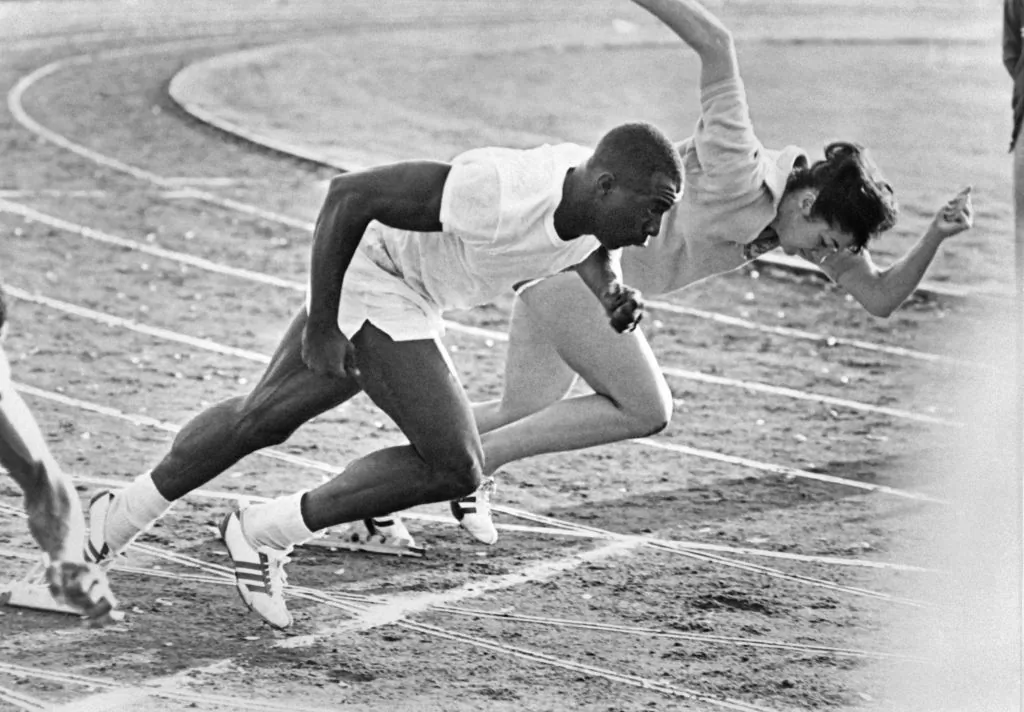American runner Bob Hayes and New Zealand's Doreen Porter during a start-training session as part of 1964 Tokyo Olympic Games. (Photo by -/AFP via Getty Images)