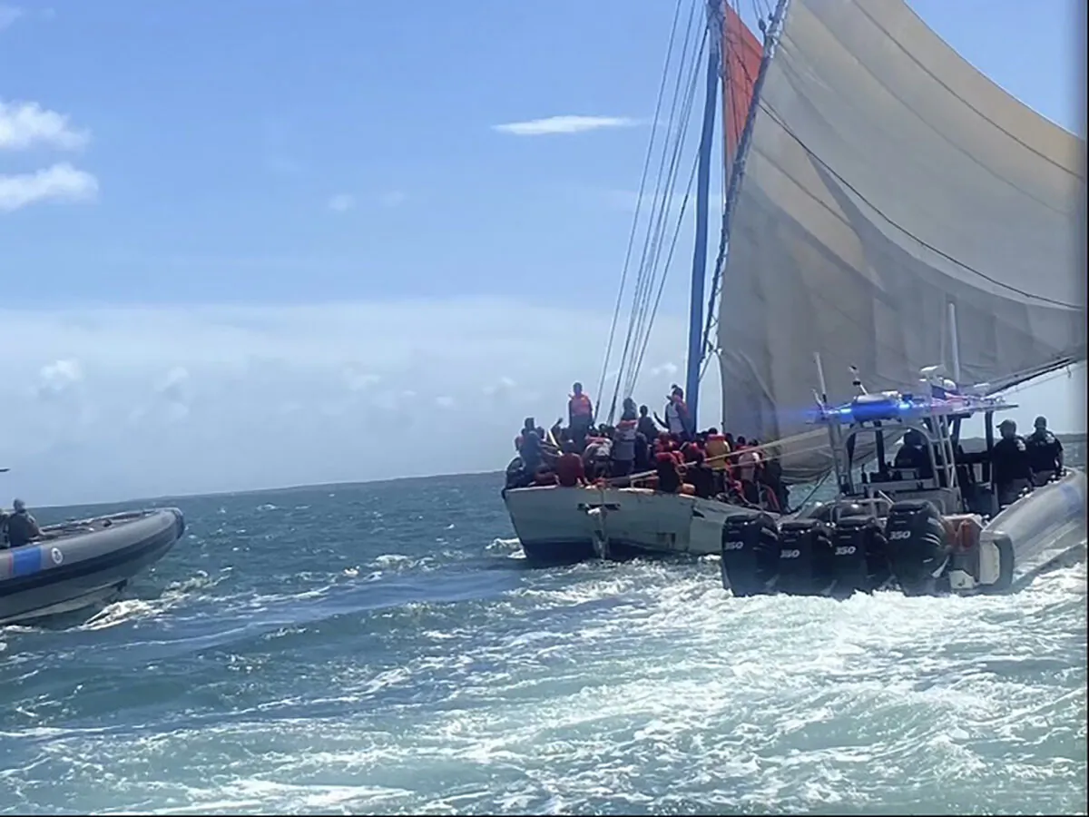 Rescue crews safely transfer people from a grounded vessel believed to be carrying migrants, to U.S. Coast Guard ships, off the coast of Key Largo, Fla., near the gated community of Ocean Reef, on Aug. 6, 2022. (Courtesy of U.S. Coast Guard via AP)